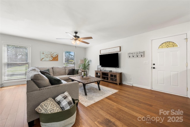 living room featuring hardwood / wood-style flooring, baseboards, visible vents, and ceiling fan