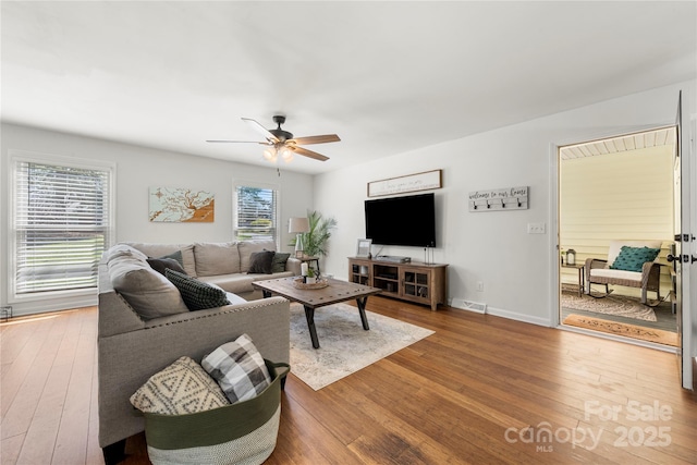 living room with hardwood / wood-style flooring, baseboards, visible vents, and ceiling fan