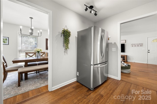 kitchen featuring a notable chandelier, freestanding refrigerator, baseboards, and wood finished floors