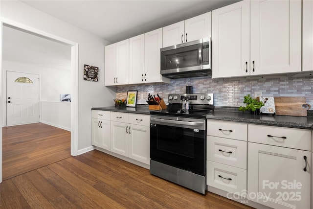 kitchen featuring dark countertops, tasteful backsplash, dark wood-type flooring, appliances with stainless steel finishes, and white cabinets