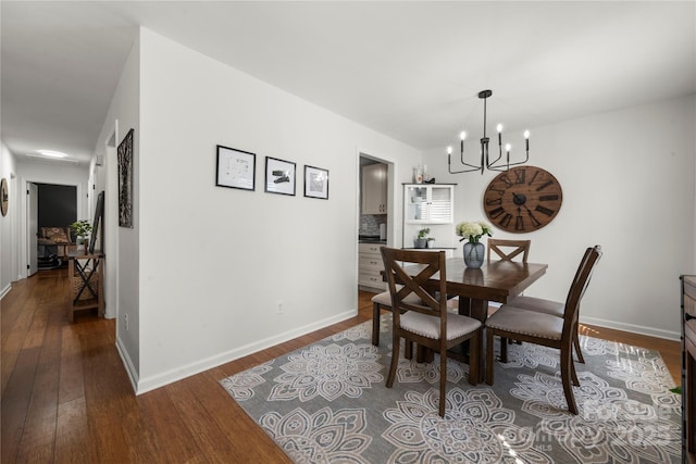 dining room with an inviting chandelier, baseboards, and dark wood-style flooring