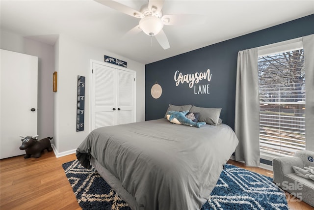 bedroom featuring a closet, baseboards, ceiling fan, and wood finished floors