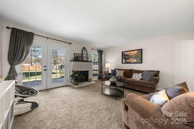 living area featuring french doors, a brick fireplace, and carpet flooring