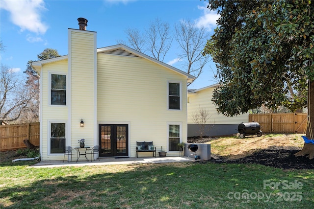 rear view of property featuring a lawn, a patio, fence, french doors, and a chimney