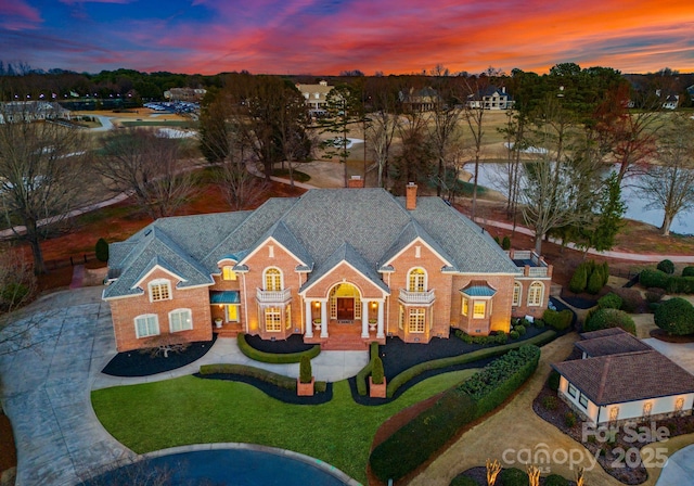 colonial-style house with brick siding, driveway, a front yard, and roof with shingles