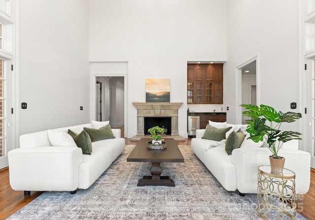 living room featuring a high end fireplace, a towering ceiling, and wood finished floors