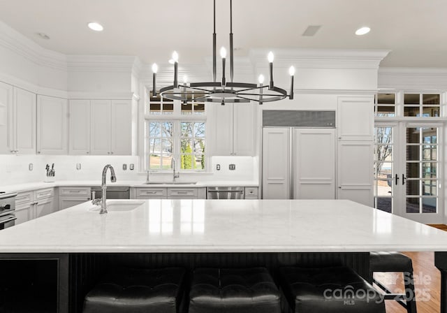 kitchen with ornamental molding, a breakfast bar, paneled refrigerator, and a sink