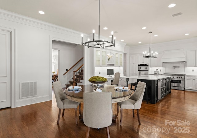 dining room with visible vents, dark wood-type flooring, a chandelier, and crown molding