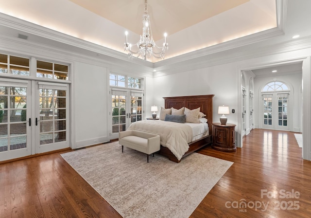 bedroom with access to exterior, french doors, dark wood-type flooring, and a tray ceiling