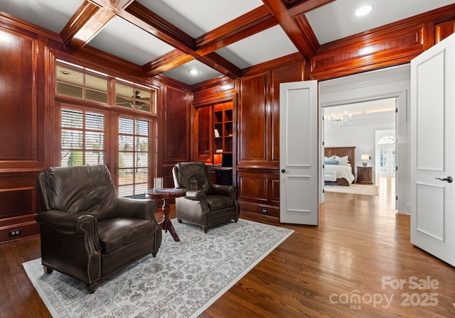 living area with wooden walls, beamed ceiling, coffered ceiling, and dark wood-style flooring