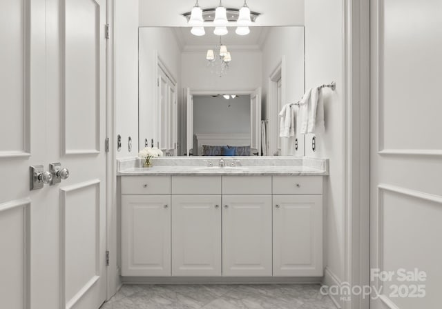 bathroom featuring marble finish floor, ornamental molding, and vanity