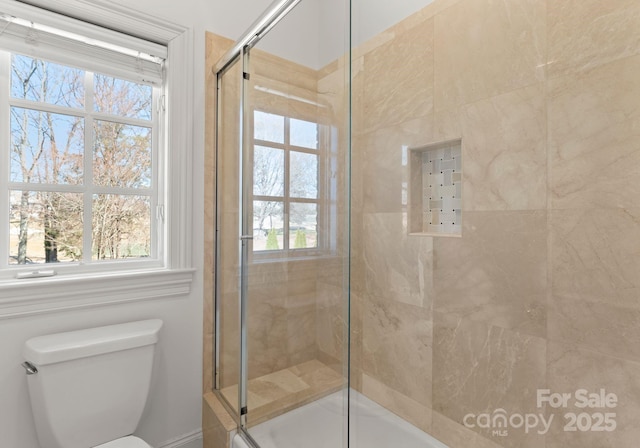 bathroom featuring tiled shower and toilet