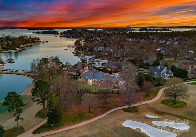 aerial view at dusk with a water view and a residential view