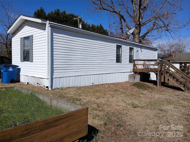 view of home's exterior featuring a wooden deck, stairs, and a yard