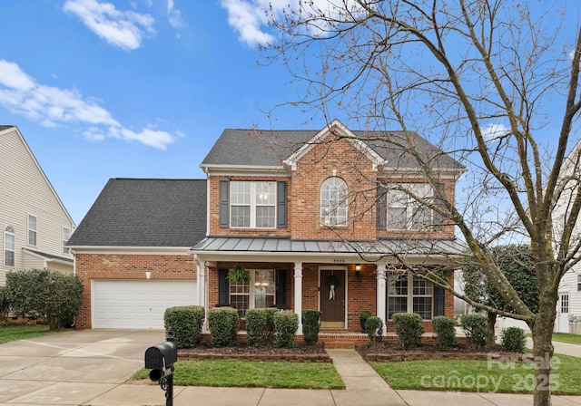 traditional-style house with driveway, covered porch, an attached garage, a shingled roof, and brick siding