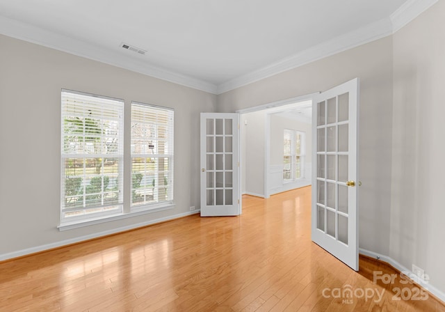 spare room featuring light wood finished floors, visible vents, french doors, and ornamental molding