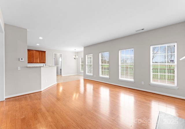 unfurnished living room with a notable chandelier, visible vents, light wood-style flooring, and recessed lighting