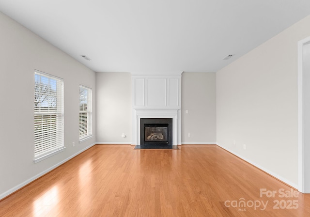 unfurnished living room featuring light wood-style flooring, a fireplace, visible vents, and baseboards