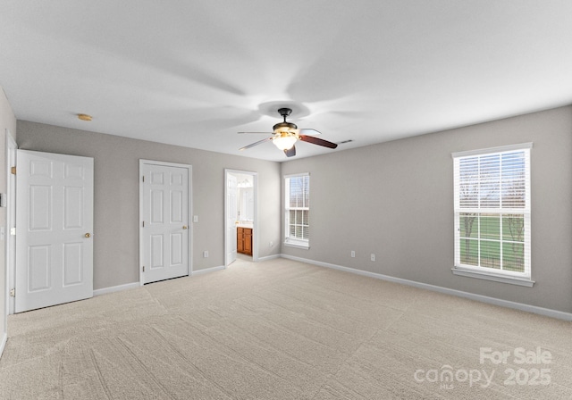 unfurnished bedroom with baseboards, multiple windows, and light carpet