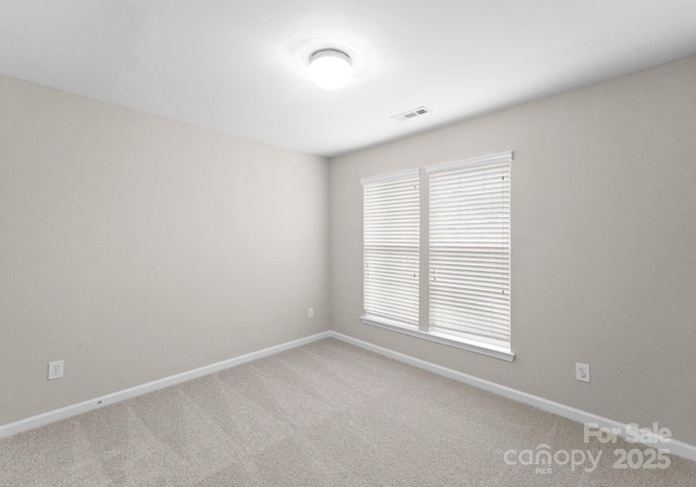 carpeted spare room featuring visible vents and baseboards