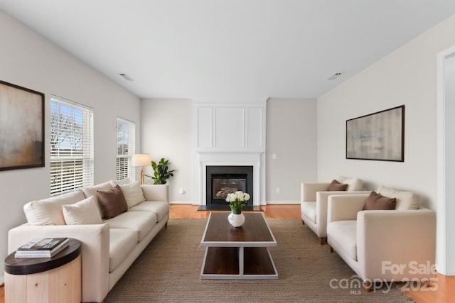 living room with a fireplace, wood finished floors, and visible vents