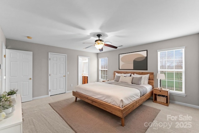 bedroom featuring baseboards, light colored carpet, and ensuite bath