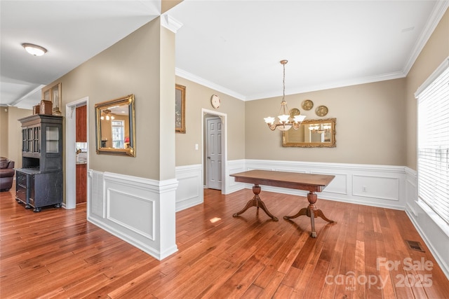 dining room featuring visible vents, a notable chandelier, wood finished floors, and wainscoting