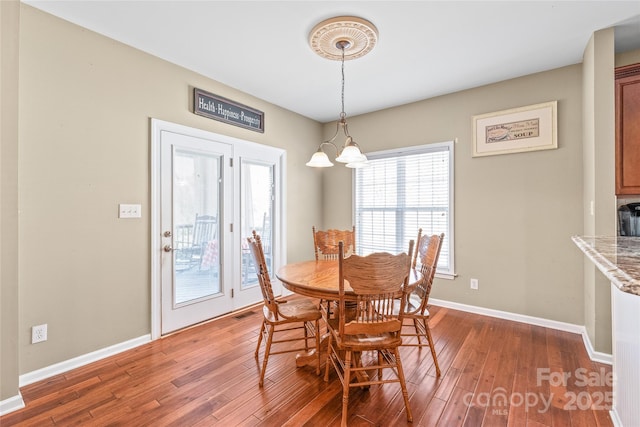 dining room featuring a chandelier, baseboards, and wood finished floors