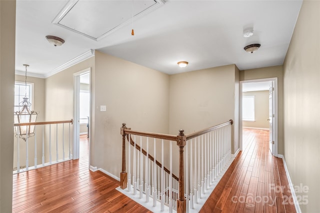 corridor featuring attic access, hardwood / wood-style flooring, an upstairs landing, and baseboards