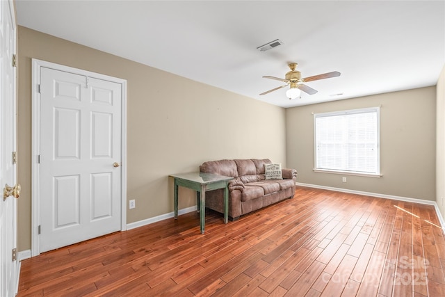 living area with visible vents, a ceiling fan, baseboards, and wood finished floors