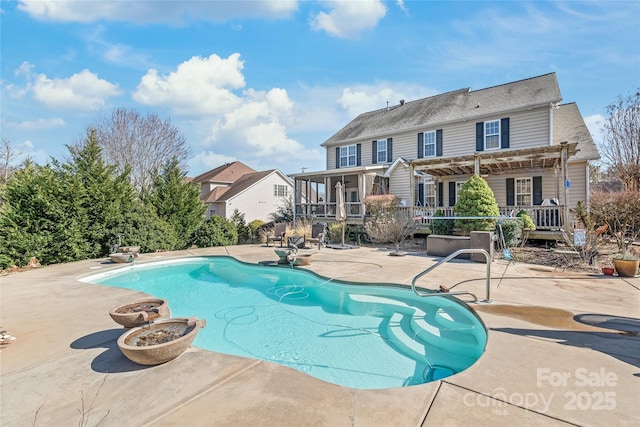 pool with a pergola, a patio, a fire pit, a sunroom, and a wooden deck