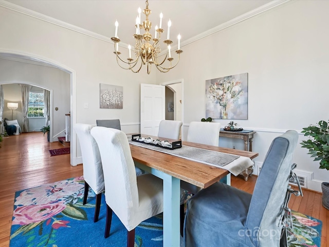 dining space featuring visible vents, ornamental molding, hardwood / wood-style flooring, arched walkways, and baseboards