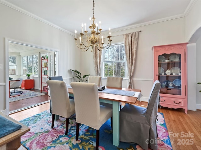 dining space featuring an inviting chandelier, crown molding, and wood finished floors