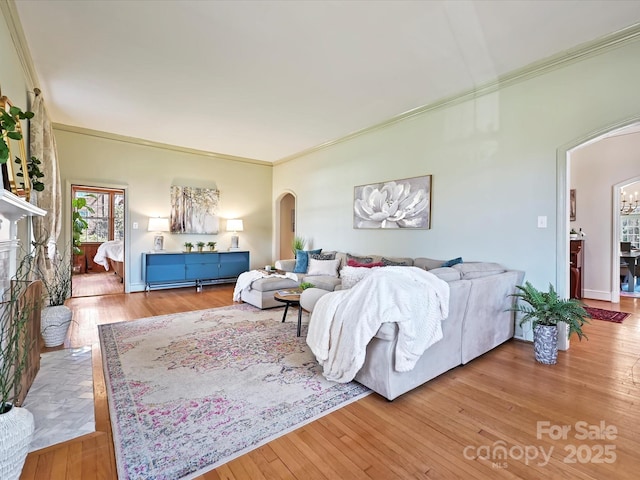 living area with arched walkways, wood finished floors, a fireplace, and crown molding