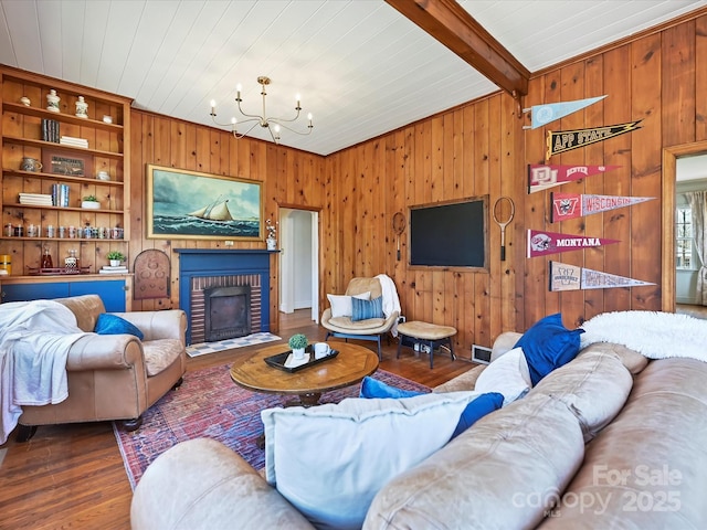 living area with wood finished floors, an inviting chandelier, beam ceiling, wood ceiling, and a brick fireplace