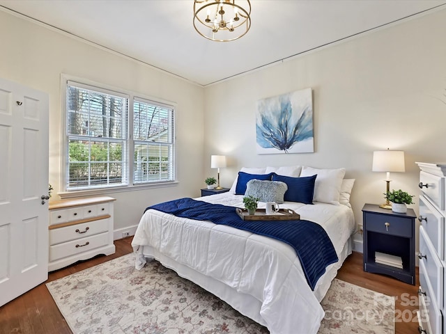 bedroom with baseboards, an inviting chandelier, and wood finished floors