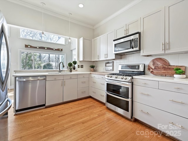 kitchen featuring a sink, tasteful backsplash, appliances with stainless steel finishes, crown molding, and light countertops