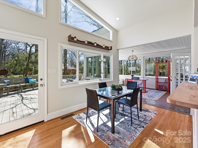 dining room featuring hardwood / wood-style flooring, visible vents, baseboards, and a towering ceiling