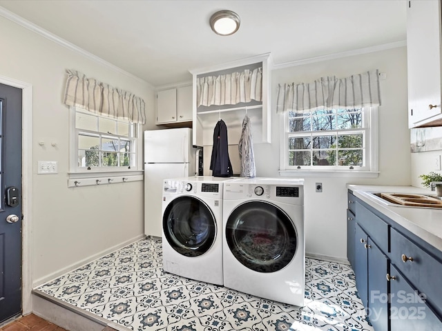 laundry area featuring a sink, washing machine and dryer, cabinet space, crown molding, and baseboards