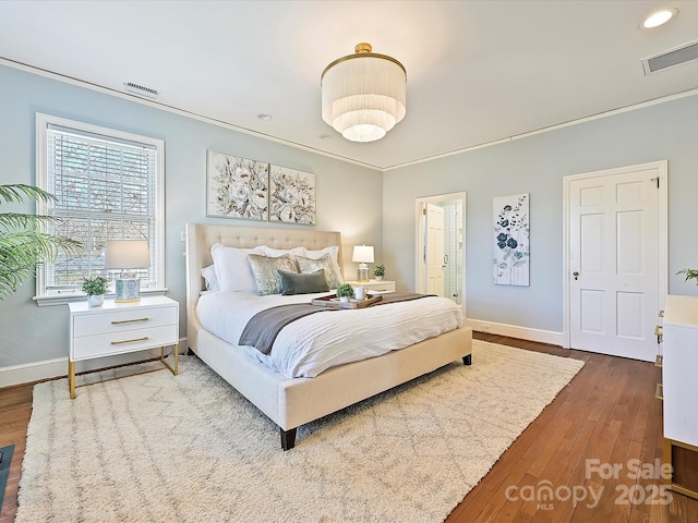 bedroom with visible vents, baseboards, crown molding, and hardwood / wood-style flooring