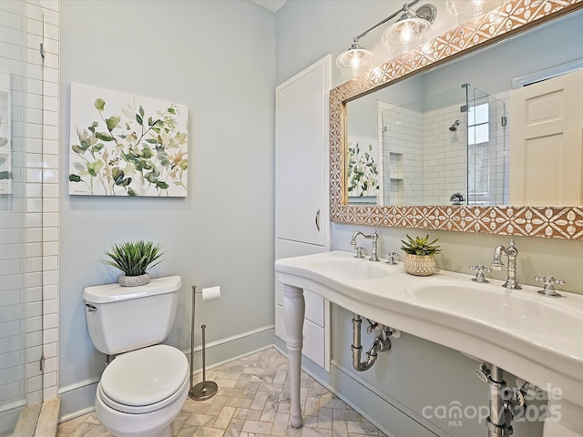 bathroom with toilet, baseboards, and a stall shower