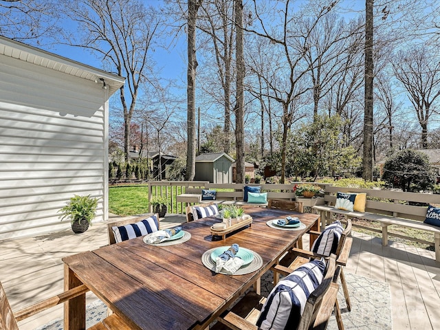 wooden deck with an outbuilding, a shed, and outdoor dining area