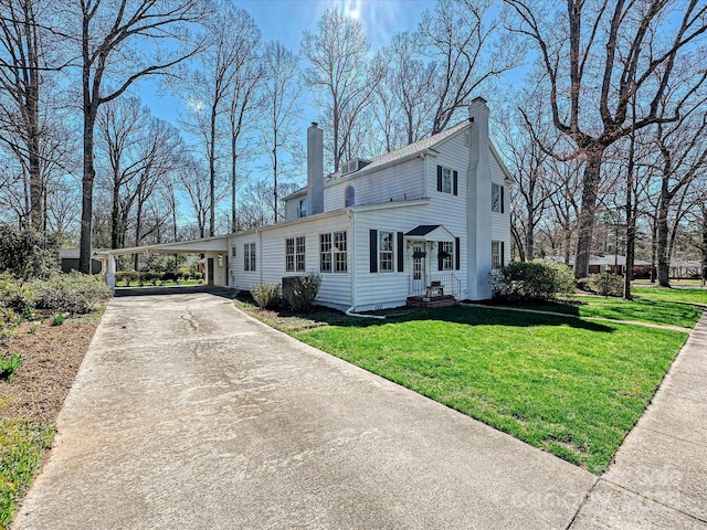 view of front of house featuring an attached carport, driveway, a front yard, and a chimney