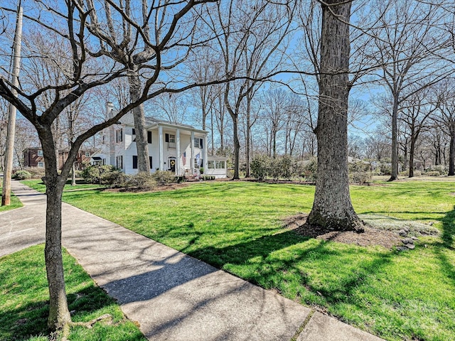 view of front of home featuring a porch, a front lawn, and a chimney