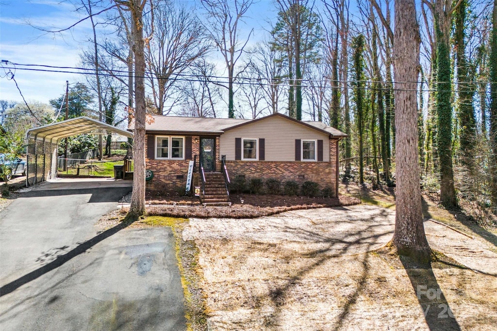 view of front of house with brick siding, a detached carport, and driveway