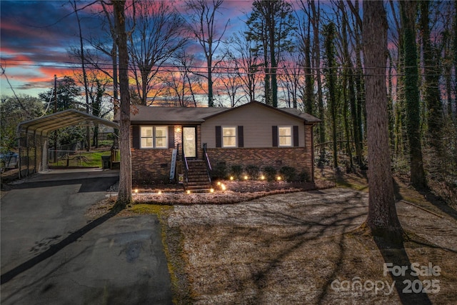 view of front facade featuring aphalt driveway, a detached carport, and brick siding