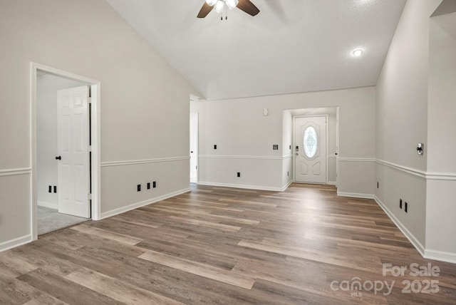 foyer entrance featuring ceiling fan, baseboards, high vaulted ceiling, and wood finished floors