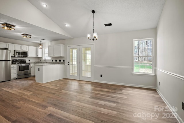 kitchen featuring wood finished floors, visible vents, vaulted ceiling, appliances with stainless steel finishes, and white cabinetry