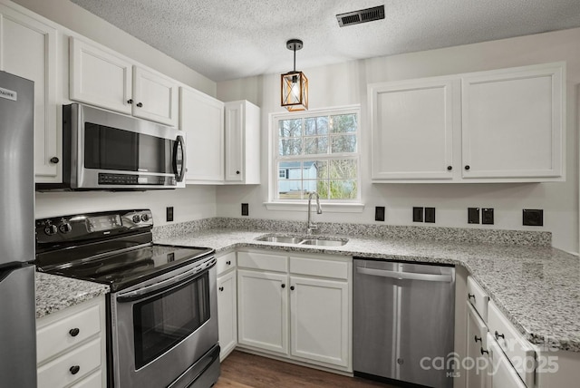 kitchen featuring visible vents, a sink, stainless steel appliances, white cabinets, and a textured ceiling