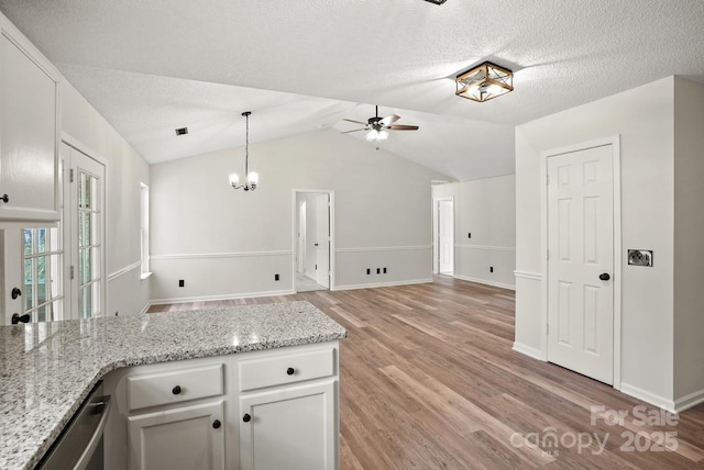 kitchen with open floor plan, white cabinets, vaulted ceiling, and light wood finished floors